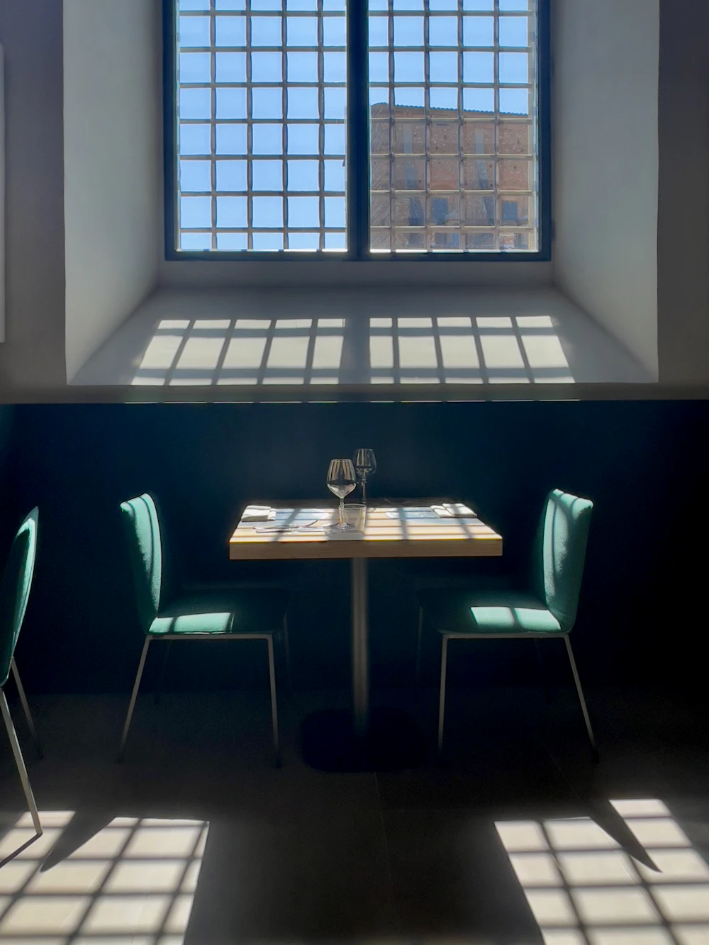 Two chairs across a table in a sunlit room.